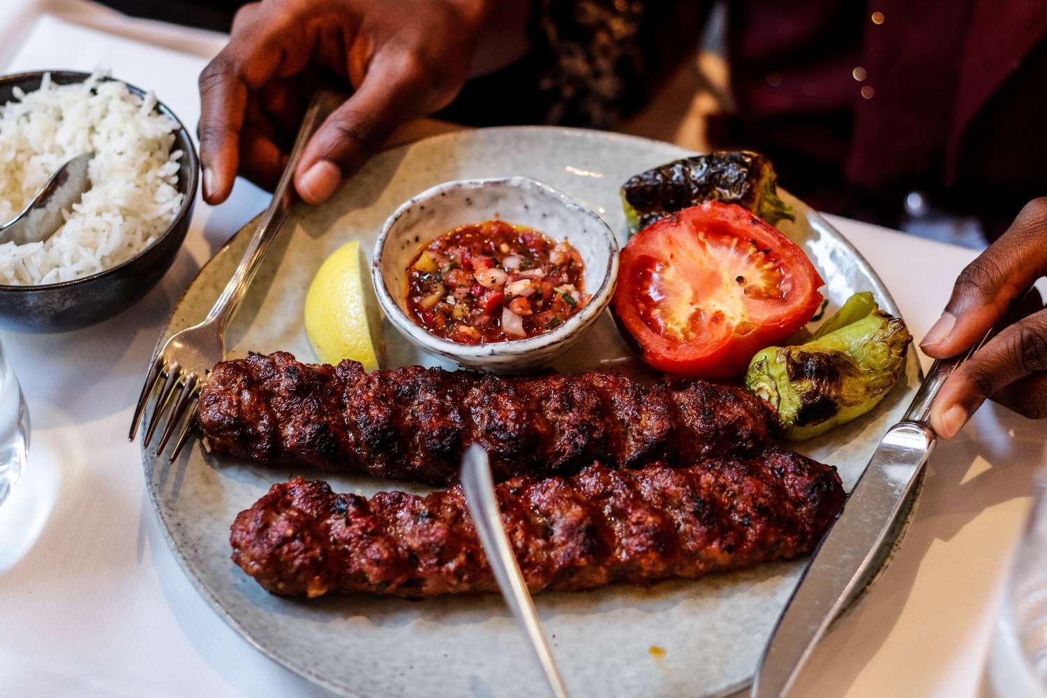 Kebabs served with rice and grilled tomato